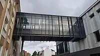 A glass corridor above the ground, connects two different buildings.