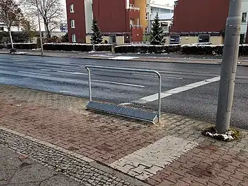 A common waiting aid combining a footrest and a handrail. highway=cyclist_waiting_aid footrest=yes handrest=yes side=left