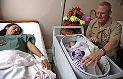 U.S. Navy Cmdr. Mark Becker, right, the mission commander of Southern Partnership Station 2011, presents an Ecuadorian newborn with a stuffed animal during tour of Clinica Fae in Ecuador Jan. 6, 2011. Stuffed animals were delivered as part of Project