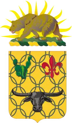 Shield: Or, chain mail Vert, in chief a prickly pear cactus of the last and a fleur-de-lis Gules and in base a carabao affronté Sable. Crest: That for the regiments and separate battalions of the California Army National Guard: On a wreath of the colors Or and Vert, the setting sun behind a grizzly bear passant on a grassy field all Proper.