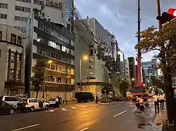 Scaffolding hanging from the side of a building and partially lying on a road, which has been cordoned off.
