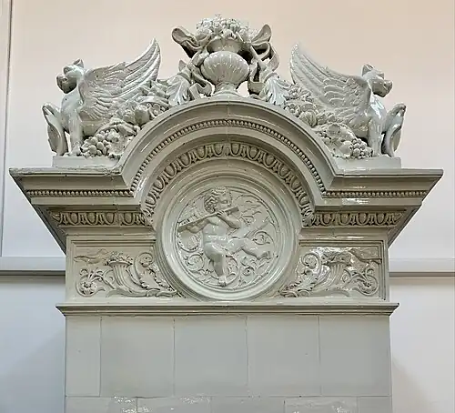 Upper part of a Neoclassical tiled stove, decorated with griffins, garlands (aka festoons), a medallion with a cerub (aka putto), cornucopias and foliage spirals, in the principals' house of the Central Girls' School, Bucharest, unknown designer, 1890