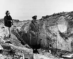 CY Cook (left) and LCDR Knapper of USS Texas (BB-35) inspecting bombardment damage, Pointe du Hoc, France, 1944.