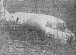 A black-and-white photograph of a wrecked airplane in a field