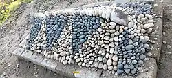 A grave decorated with Indus River stones — a traditional Pashtun funerary practice in Hund.