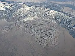 Aerial photo of the Great Sand Dunes partially surrounded by a mountains range with ridges and valleys