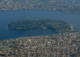 A forested peninsula surrounded by a lake and urban neighborhoods