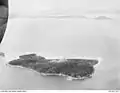 Aerial view of North Brook Island with smoke rising from a bomb test