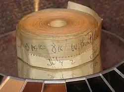An aged roll of paper tape perhaps 1–2 inches (2.5–5.1&nbsp;cm) wide; on the outside is written "BASIC 8K without cassette" and "July 2" in blue biro pen.