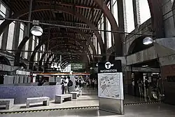 Interior of a railway station with large glass windows and arches under a flat ceiling