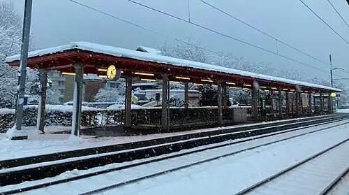 A canopy-covered platform covered in snow, with two railway tracks in the foreground.