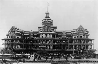 A black-and-white photograph of a grand beach-side hotel
