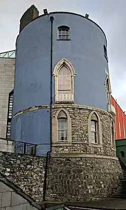 A color photograph of a cylindrical stone tower painted blue