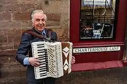 Wilkie playing his accordion outside his shop in Perth city centre