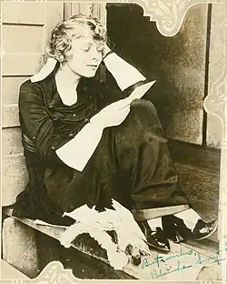 Blanche Sweet seated reading a letter, wearing a dark dress
