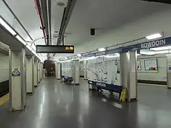 A wide subway platform with white columns
