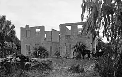 Photo of a two-story tabby house missing its roof, windows and interior