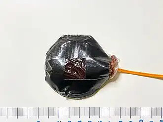 A bullet hit squib device with approx. 25&nbsp;g of fake blood in a plastic pouch, assembled with duct tape.