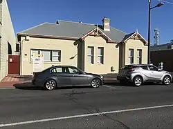 One-storey tan-coloured building on city centre street with parking