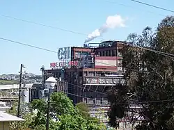 A large industrial building seen through trees.