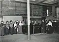Female staff of the Old Main posing in front of the charging booth, black-and-white