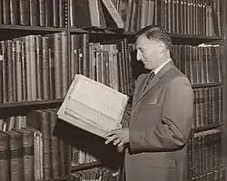 Fergusson examining historic letters in front of a bookshelf