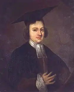 Half length and dark portrait of a serious and slightly plump man wearing a black academic gown with white collar, ruffled cuff, and a large mortarboard.
