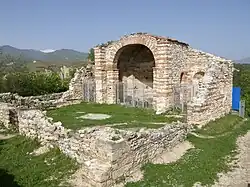 Southwest view of a partially ruined medieval church, with the eastern part mostly extant