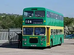 Green and yellow double-decker entering a car park