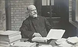 Photograph of Jean-Vincent Scheil at a desk with piles of books and paper