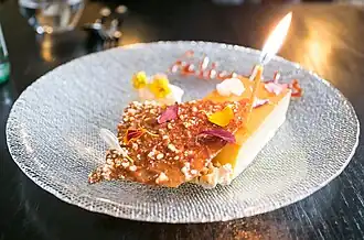 A slice of flan accompanied with a birthday candle.