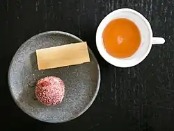 A cup of guava punch with a piece of sugar cane and cinnamon bread.