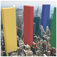 A city with four colored blocks (from left to right: Yellow, Red, Blue and Green) much taller than the regular buildings