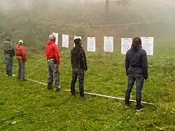 A line of people in front of targets with guns in holsters.