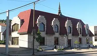 Beige stone building with five double windows rising into the red roof
