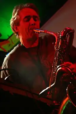 Head and shoulders photograph of a musician playing a saxophone