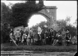 A black and white photograph of a group of people in acting costume