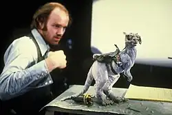 A photo of Phil Tippett observing a tauntaun miniature for stop-motion animation