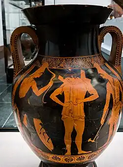 Photograph of a Greek vase: a young man, central, puts on armour: the archers wear the floppy Phrygian cap associated with Scythians.