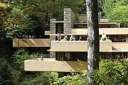 The concrete terraces on Fallingwater's southern facade from across Bear Run. In the center is the limestone chimney.