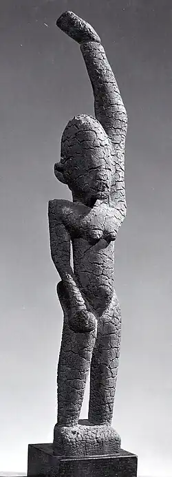 Black and white picture of a female figure with raised arm; 15th–17th century; wood (ficus, moraceae), sacrificial materials; height: 44.8&nbsp;cm (175⁄8 in.); by the Tellem people; Metropolitan Museum of Art (New York City)
