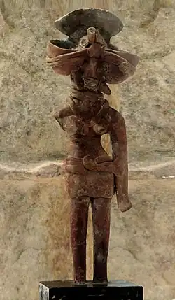 Mother Goddess wearing tight-fitted short skirt part fastened with a broad waistband using a medallion like clasp, necklaces, ear-ornaments, Mohenjo-daro.