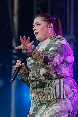 A young brunette woman sitting on a bench.