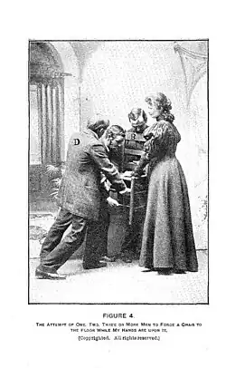 People hold a press the chair firmly downwards with intense pressure while Hurst places her hands on top of the chair.