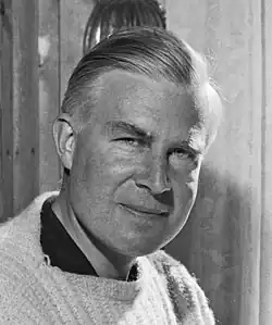 Black-and-white photo of a man with combed hair wearing a knit sweater over a dark shirt
