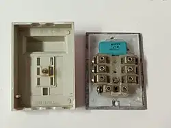 A GTN-6 plug disassembled into two parts, the plastic cover on the left and the internal electronics on the right. Above the terminal block is visible a blue capacitor.