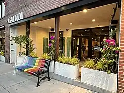 Entrance to a restaurant named Gai Noi. A rainbow colored bench is in front.
