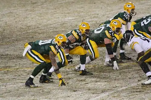 American Football players line up against each other and crouch down into an isometric press position. This allows them to rush forwards more powerfully when the play begins; this is particularly useful in regard to tackling or blocking an opponent.
