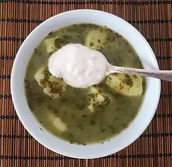 Green borscht with spinach and potatoes, topped with smetana