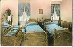 Two small beds in a small room with a dresser and two windows